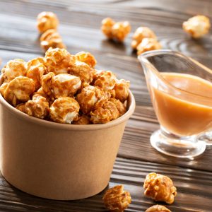 Caramelized popcorn in paper bucket on wooden table